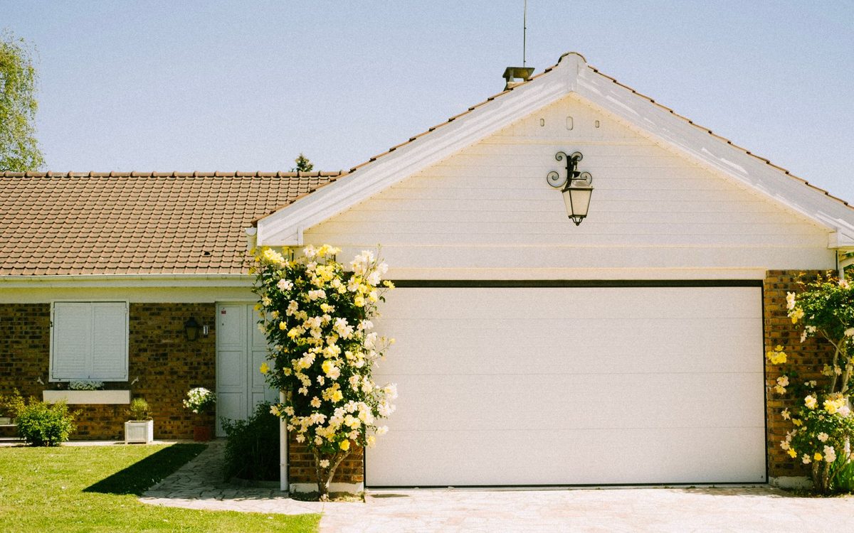 Garagem residencial em condomínio fechado com portão e jardim