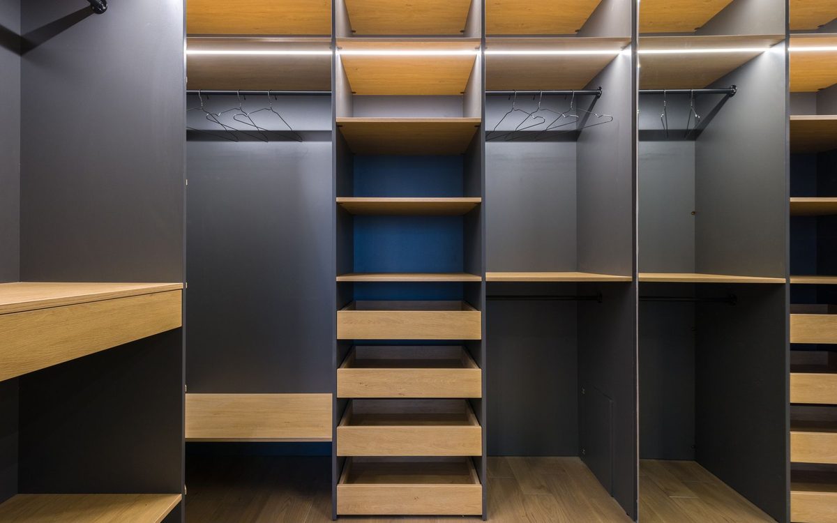 Closet com móveis planejados em madeira e iluminação embutida