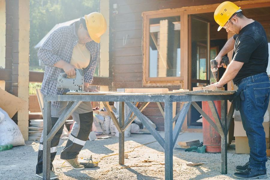 Equipe trabalhando com ferramentas elétricas na estrutura de madeira de uma obra
